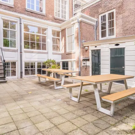 Exterior view of Herengracht 582-584 office showing a courtyard with picnic tables, ideal for breaks in the Amsterdam Canal Belt.