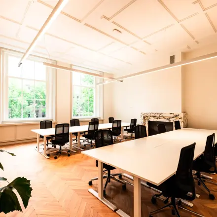 Furnished office space with desks and chairs ideal for rent at Keizersgracht 264, offering a bright workspace with large windows in Amsterdam Canal Belt.