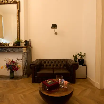 Charming office space at Keizersgracht 391A with a classic leather couch, a decorative fireplace, and ambient lighting, ideal for relaxing meetings in the Amsterdam Canal Belt.