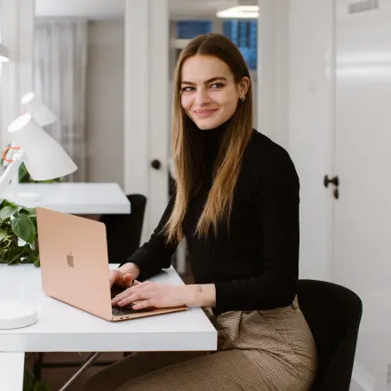 Businessperson working on a laptop in a bright office space with modern decor at Keizersgracht 62-64, a sought-after location in Amsterdam Canal Belt for office space rental.