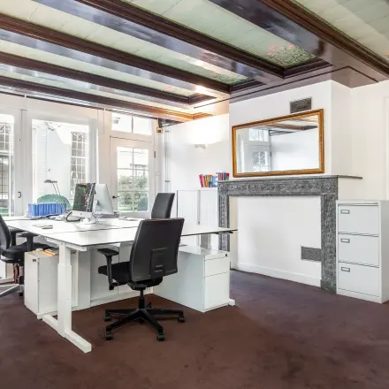 Bright office space with desks, chairs, and a view of the garden, suitable for rent office space at Keizersgracht 62-64, Amsterdam Canal Belt.