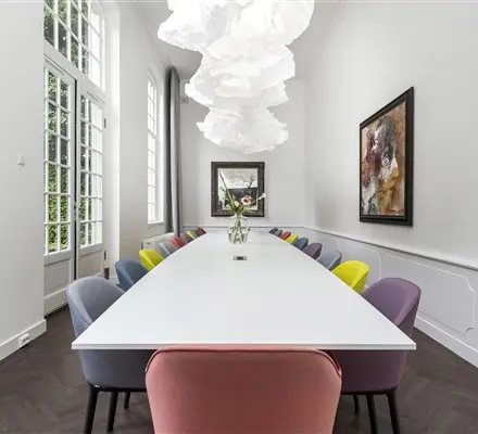 Bright, modern office space rental with a long table and colorful chairs, located at Keizersgracht 62 – 64, Amsterdam Canal Belt.