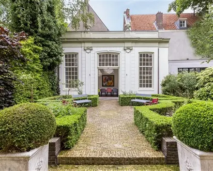 Exterior of office space rental at Keizersgracht 62-64 in Amsterdam Canal Belt, featuring a lush garden path leading to a historic building facade.
