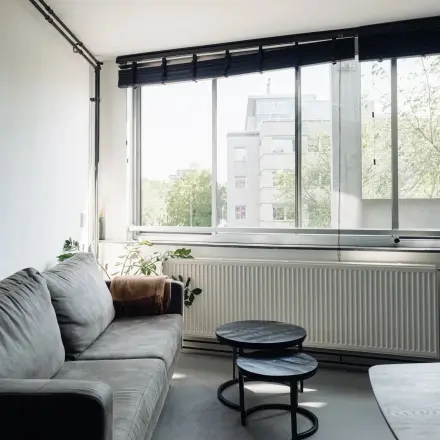 Bright office space with a cozy gray sofa, nested tables, and large windows at Weesperstraat 394-396, perfect for office space rental in Amsterdam Canal Belt.
