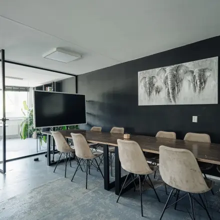 Modern office space with a large wooden table, chairs, and wall artwork at Weesperstraat 394-396, perfect for office space rental in Amsterdam Canal Belt.