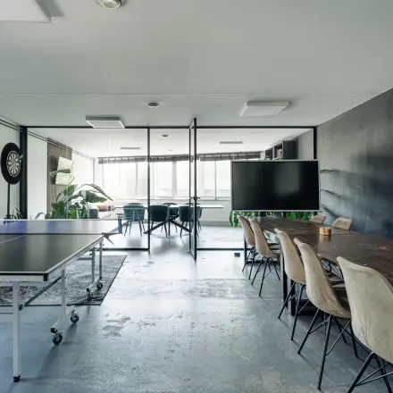 A spacious office at Weesperstraat 394-396 with a meeting table, wall art, dartboard, and ping pong table, ideal for office space rental in Amsterdam Canal Belt.