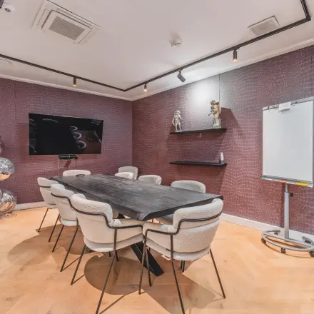 Trendy conference room at Hekelveld 8-10 with a long sleek table, modern chairs, and creative decor, perfect for office space rental in Amsterdam Center.