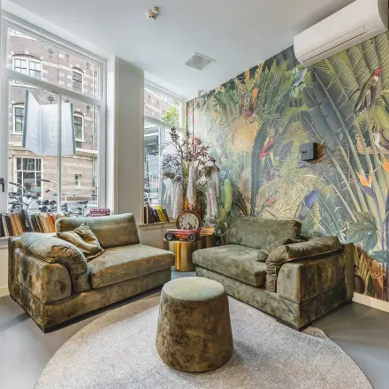 Cozy lounge area with plush seating and colorful mural at an office space available for rent in Amsterdam Center.