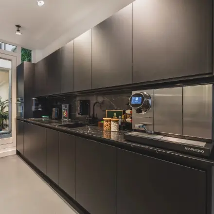 Modern pantry area at Hekelveld 8-10 in Amsterdam Center, featuring sleek, dark cabinets and coffee-making facilities, ideal for office space rental.
