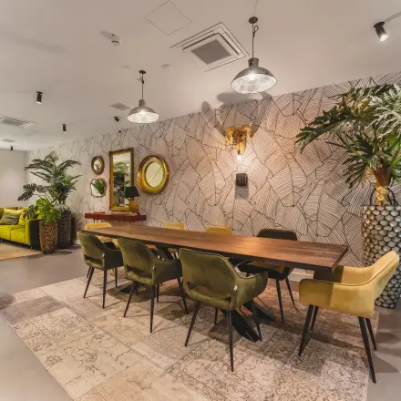 Stylish office space at Hekelveld 8-10, Amsterdam Center, featuring a large wooden table, plush chairs, and a vibrant plant display, ideal for workspaces. Suitable for office space rental.