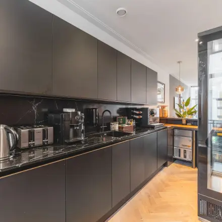 Modern pantry area with black cabinets and essential appliances, ideal for a break during office space rental at Hekelveld 8-10, Amsterdam Center.