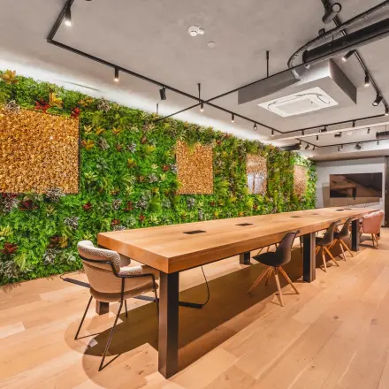 Modern workspace with a long wooden table, chairs, and a vibrant green wall in the office at Hekelveld 8-10, Amsterdam Center.