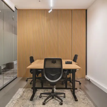Furnished office space with wooden table and chairs, featuring a stylish wood-paneled wall in Amsterdam Center.