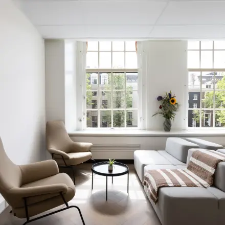 Bright and inviting office space for rent in Amsterdam Center with modern furnishings and large windows overlooking the cityscape.