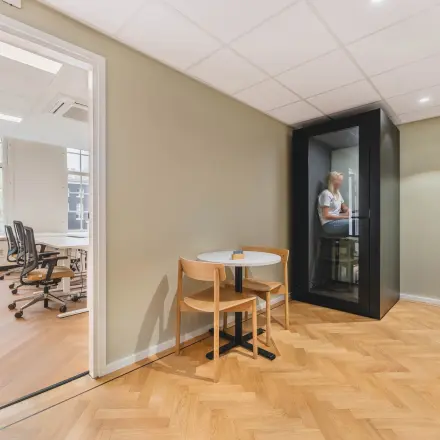 A furnished interior office space at Herengracht 471, Amsterdam Center, featuring a meeting booth and desk, ideal for office space rental.