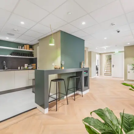 Modern office space rental at Herengracht 471, Amsterdam Center with a sleek kitchenette and seating area, suitable for those seeking an office to rent in a professional setting.