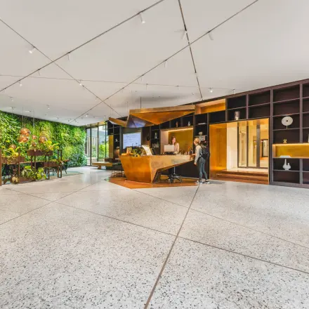 Modern reception area at office space rental on Herengracht 471, Amsterdam Center, featuring a green wall and sleek furnishings. Two individuals engaged in reception tasks.