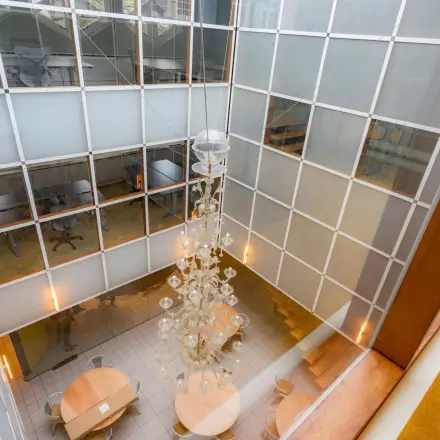 A modern, bright atrium with circular tables and a large chandelier, perfect for office space rental in Amsterdam Center.