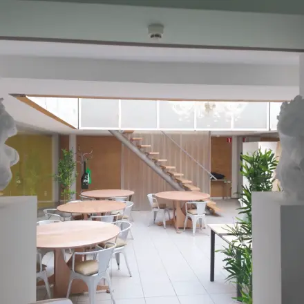 Spacious office area at Kerkstraat 204, Amsterdam Center, featuring round tables, chairs, and greenery ideal for office space rental.