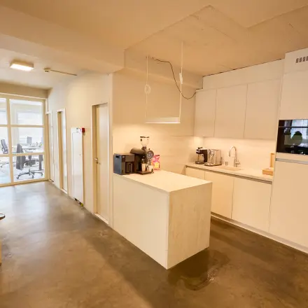 Bright office space with a kitchenette in Amsterdam Center, featuring modern furnishings and a glimpse of the workspaces area. Ideal for office space rental.