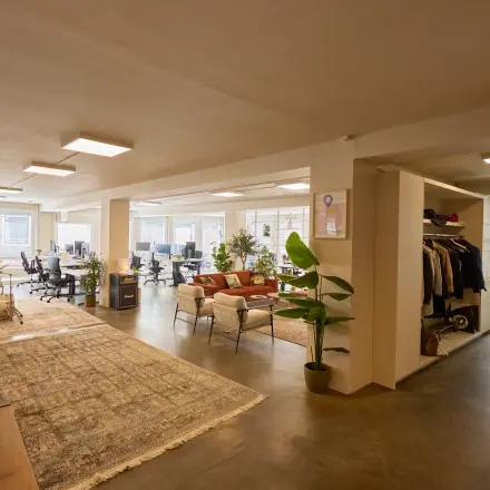 Spacious office space with various workstations, a comfortable lounge area, and abundant natural light, perfect for office space rental in Amsterdam Center.