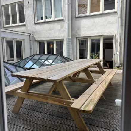 Outdoor wooden picnic tables on a deck outside an office space for rent at Kloveniersburgwal 131K in Amsterdam Center.
