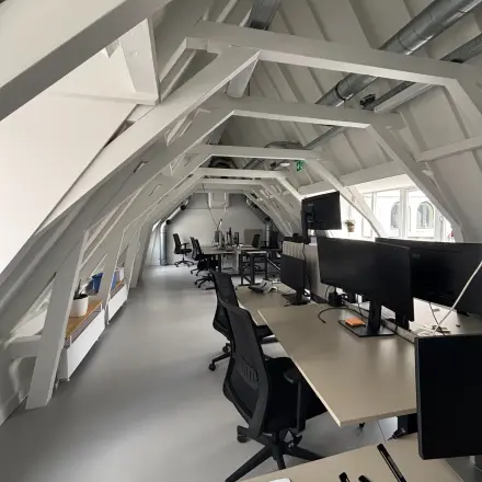 Modern office space in Amsterdam Center, featuring rows of workstations under a spacious, sloped ceiling. Ideal office to rent for collaborative work.