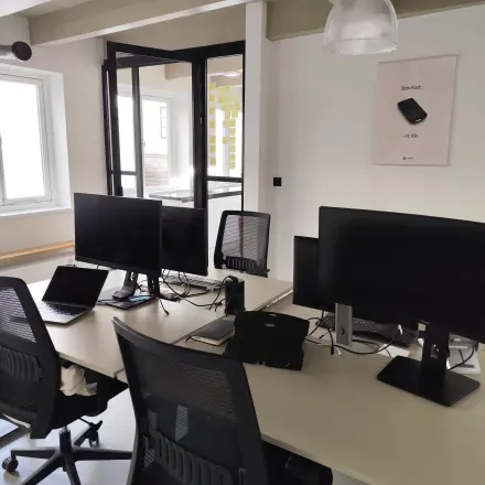 Interior of a furnished office space at Kloveniersburgwal 131K, Amsterdam Center, featuring multiple desks with monitors and chairs for rent.