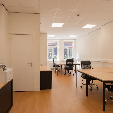 Bright office space at Korte Leidsedwarsstraat 133A 133A, Amsterdam Center featuring wooden floors, office desks with chairs, and a printer. Ideal for rent as a workspace.
