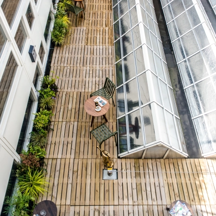 Rooftop terrace of the office located at Muiderstraat 1, Amsterdam Center. Features wooden decking, greenery, tables and chairs ideal for casual meetings or breaks. A unique spot for office space rental.