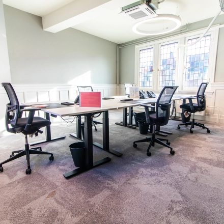Furnished office space with multiple desks and chairs, located in Amsterdam Center. Ideal for office space rental with natural light and modern decor.