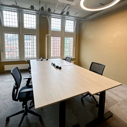 Furnished office space at Nieuwezijds Voorburgwal 104-108 in Amsterdam Center, featuring a minimalist design with tables and chairs, available for rent.