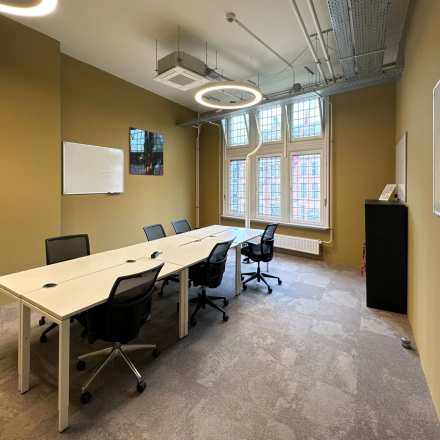 Office space rental in Amsterdam Center with a meeting table, chairs, and whiteboards, offering natural light from large windows.