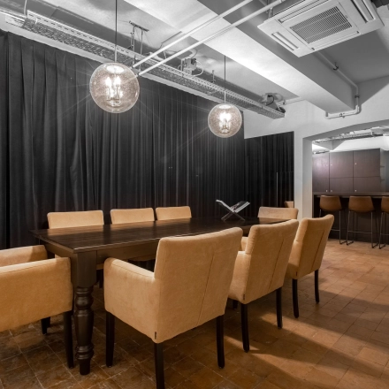 Elegant office space available for rent at Nieuwezijds Voorburgwal in Amsterdam Center, featuring a meeting area with a long wooden table and seating, adjacent to a stylish bar section.