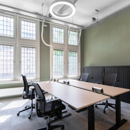 Bright and modern office space with large windows and stylish furniture, located at Nieuwezijds Voorburgwal 104-108, perfect for office space rental in Amsterdam Center.