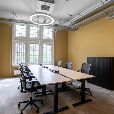 Bright office space at Nieuwezijds Voorburgwal 104-108 in Amsterdam Center, featuring a large table and chairs ideal for meetings or collaborative work, available for office space rental.