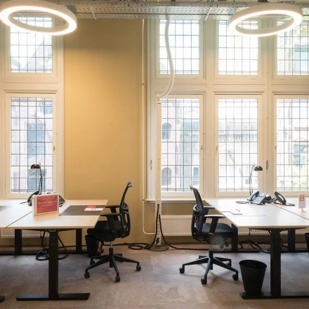 Bright office space with large windows and modern desks at Nieuwezijds Voorburgwal 104-108, Amsterdam Center, perfect for those seeking an office space rental.