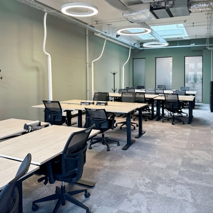 Modern office space available for rent at Nieuwezijds Voorburgwal 104-108, Amsterdam Center, featuring multiple desks and ergonomic chairs under stylish lighting in a well-lit interior.
