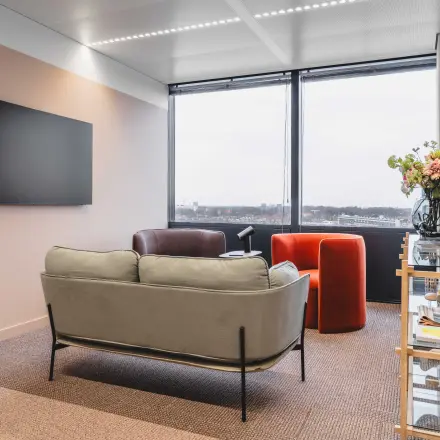 Modern office lounge space in Amsterdam Center, featuring comfortable seating and a large window view. Ideal for office space rental.
