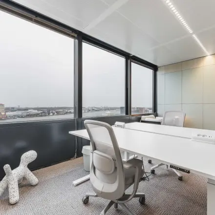 Bright office space featuring large windows and modern furniture with views of Amsterdam Center, perfect for office space rental.