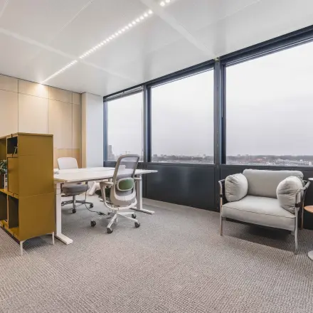 Bright office space with large windows at Piet Heinkade 55, ideal for those seeking an office to rent in Amsterdam Center. Includes a desk, chairs, and storage unit.