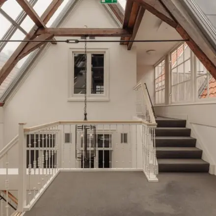 Interior of an office space at Prins Hendrikkade 14, Amsterdam Center, featuring large windows and exposed wooden beams, ideal for office space rental.