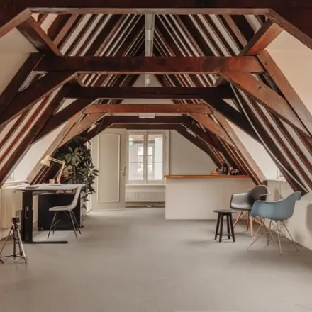 Cozy office space under wooden beams at Prins Hendrikkade 14, Amsterdam Center, available for office space rental, with modern furnishings including chairs and desks.
