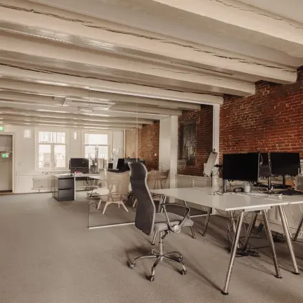 Spacious office interior at Prins Hendrikkade 14, in Amsterdam Center with desks, chairs, and exposed brick walls, perfect for office space rental.