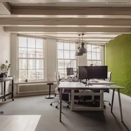 Bright office space with large windows, furnished with desks, chairs, and computers at Prins Hendrikkade 14, Amsterdam Center, perfect for office space rental.