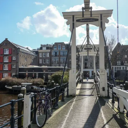 Scenic view of a bridge near office space rental at Prinseneiland 23A, Amsterdam Center with surrounding traditional buildings and a bicycle parked nearby.