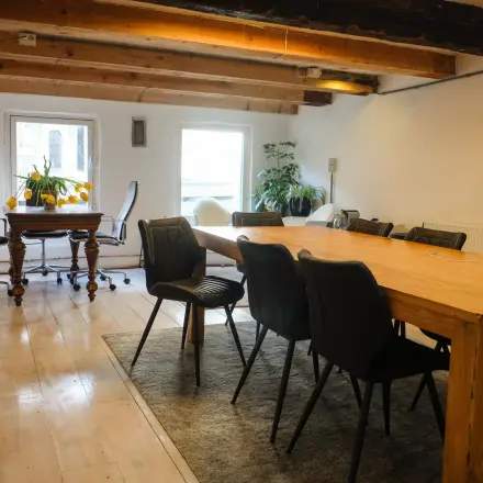 Spacious office with wooden beams and a long table, perfect for meetings, located in Amsterdam Center. Ideal office space rental with natural light.