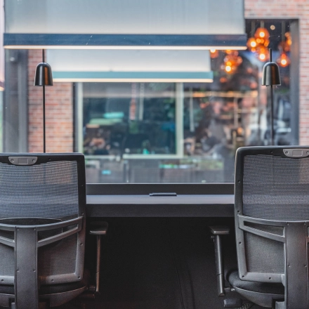 Modern office space at Raamplein 1, Amsterdam Center, featuring furnished workspaces ideal for office space rental with two ergonomic chairs and a large window view.
