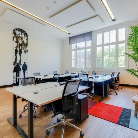 Bright office space for rent at Raamplein 1, Amsterdam Center. The furnished room features multiple desks and chairs, suitable for a collaborative work environment.