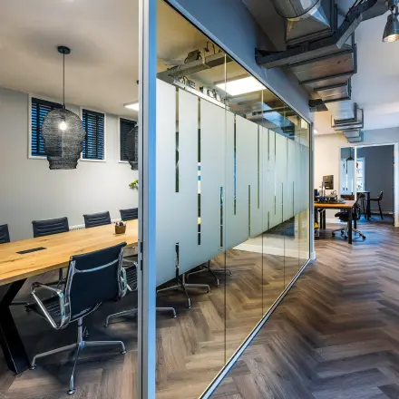 Contemporary office space in Amsterdam Center featuring a glass-walled conference room and modern furnishings, perfect for office space rental at Rapenburgerstraat 173.